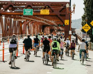 a crowd of people biking across a bridge