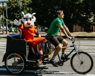 Blaze, the Trail Blazers mascot, rides by in a pedicab