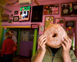 A person holds a head-sized doughnut in front of their face