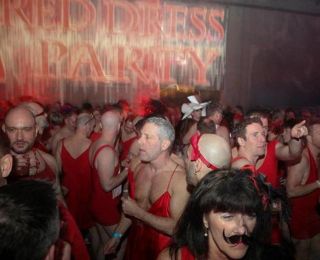 A large gathering of men, all in red dresses, celebrate at the Red Dress Party.