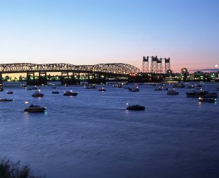 Boats on the river at dusk with a bridge in the background