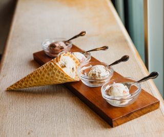 an ice cream sampler with three small bowls and one cone