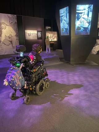 a person in a motorized wheelchair observes a museum display