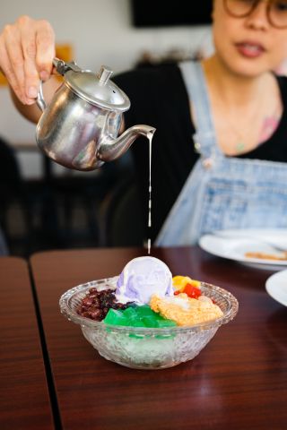 A woman drizzles sauce over a colorful dessert