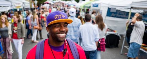a crowd explores a city street lined with vendor pop-up tents