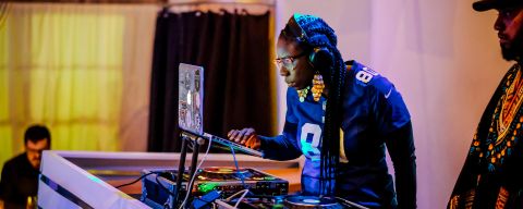 a music dj looking at a laptop connected to electronic turntables