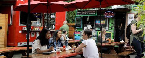 diners eating at a picnic table at an outdoor food cart pod