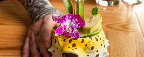 a drink with various tropical garnishes made in a glass shaped like a blowfish