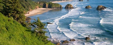 view overlooking Ecola Point, ocean waves crashing on the beach wit h large rock formations