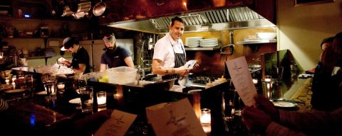 a chef stands in a small open kitchen