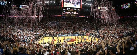 Streamers rain down over a basketball court and thousands of fans