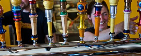 bartenders pouring beer from a line of beer taps at Hopworks Brewery