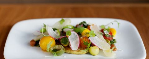 a white platter of delicately prepared, colorful vegetables on a wooden table