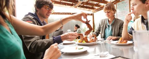 A group of people enjoying fried chicken wings, a favorite at Pok Pok