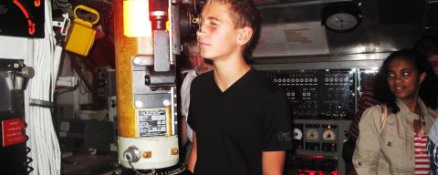 an adolescent boy looking through a submarine scope