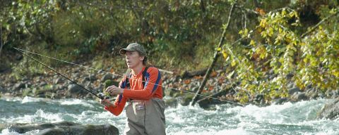 a fisherman flyfishing in a river
