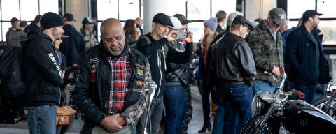 Spectators look at motorcycles in a warehouse