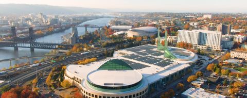 aerial view of Oregon Convention Center on a clear, sunny day with the Willamette River off to one side and surrounded by fall color in the trees