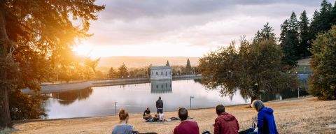 people enjoy a picnic at sunset looking out over a reservoir