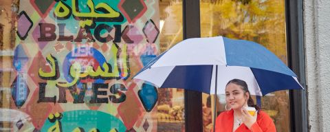 a woman holding an umbrella and coffee cup
