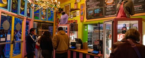 people stand in a lobby decorated with art, colors, and menus on the wall