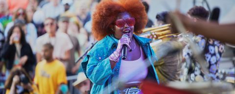 a colorfully-dressed performer sings on stage in front of musicians