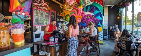 someone orders at a restaurant that is colorfully decorated, people fill the chairs in the background