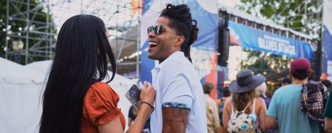 two people laughing with a crowd and stage in the background