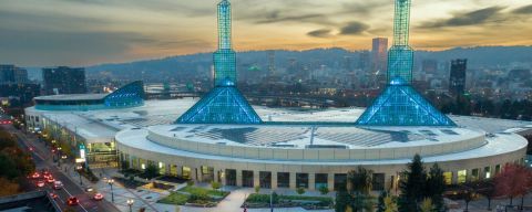 a vast building with two spires at sunset with the city skyline and hills in the background