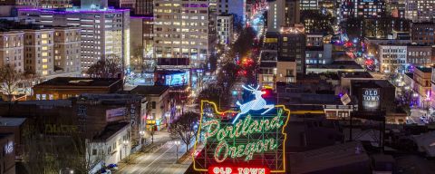 downtown and old town Chinatown are lit up at night behind the Portland stag sign