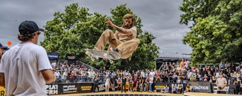 A skateboarder flies through the air while a crowd looks on.