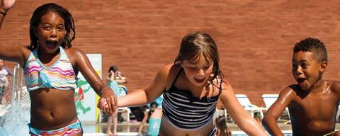 three children holding hands in a pool