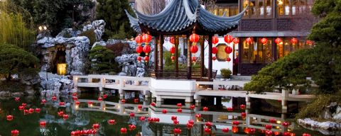 red lanterns float in water in front of a Chinese-style building
