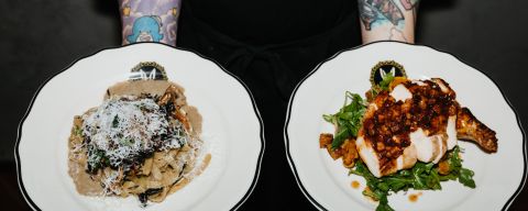 a person with tattooed forearms holds two plates of food