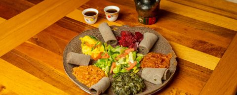 a large plate of colorful food, a pitcher and two teacups on a wooden table at Enat Kitchen in Portland