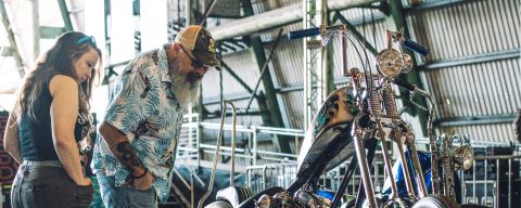 a man and a woman look at a custom motorcycle on display