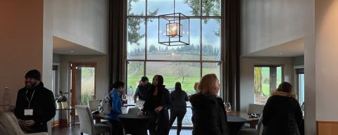 small groups of people visiting in front of a large window at Stoller winery
