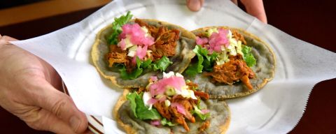 three beautifully made panuchos being held on a plate
