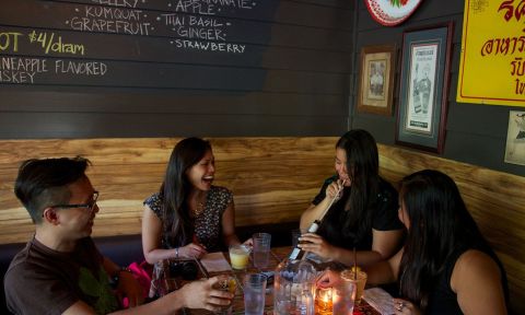 A foursome laughing over drinks at the Whiskey Soda Lounge.