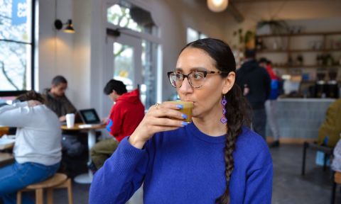 a person sips an espresso drink in a bright airy café