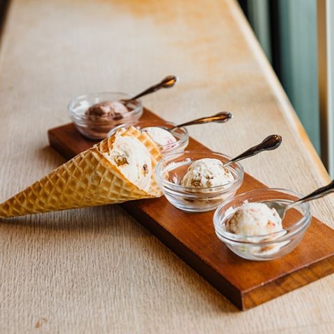 an ice cream sampler with three small bowls and one cone