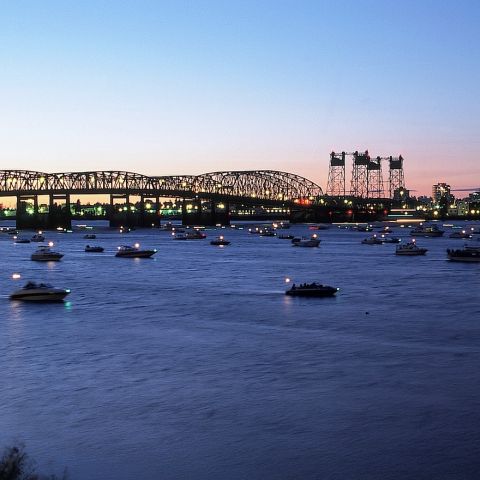 Boats on the river at dusk with a bridge in the background