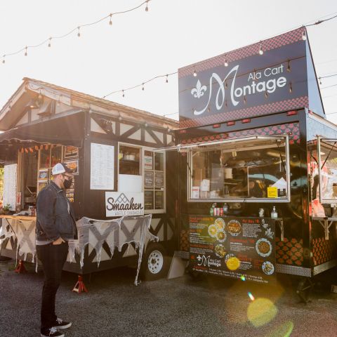 A man wearing a face mask waits in front of a food cart