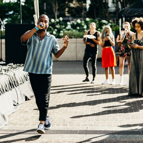 a person raps into a microphone in front of a small crowd