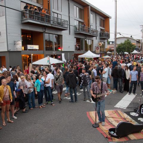 crowd gathered around a street musician as he performs at Last Thursday art walk