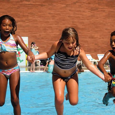 three children holding hands in a pool