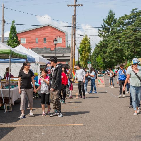 Patrons of all ages shop at a famrers market in an urban parking lot