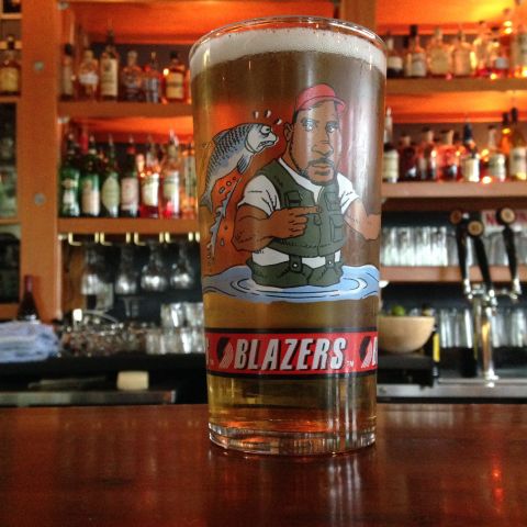 a vintage Portland Trail Blazers glass sits on a bar with rows of bottles behind it