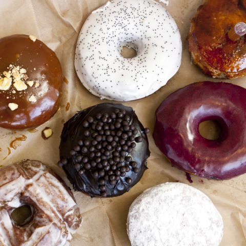 an overhead view of seven gourmet doughnuts in various styles and flavors
