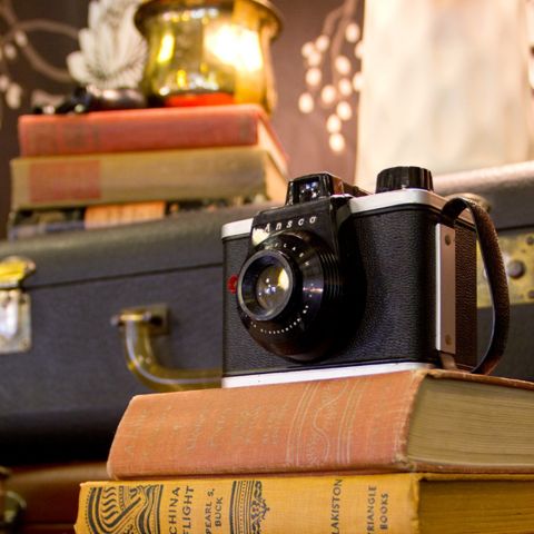 a vintage camera and suitcase displayed along with old hardcover books